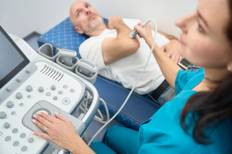 Woman performing ultrasound examination of elbow joint to a man