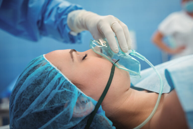Surgeon adjusting oxygen mask on patient mouth in operation theater