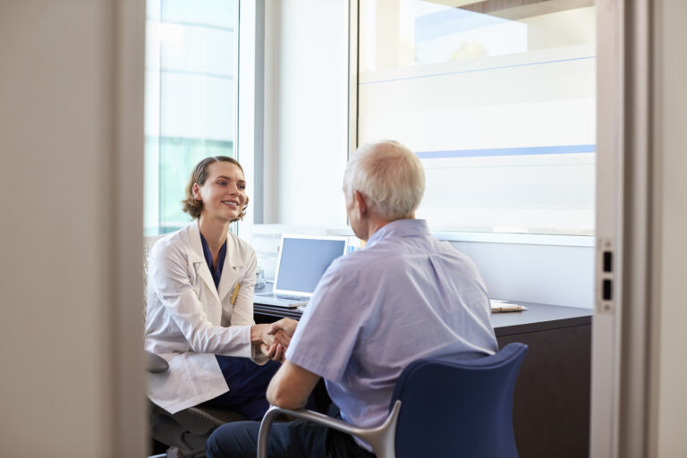 Doctor Shaking Hands With Mature Male Patient In Office